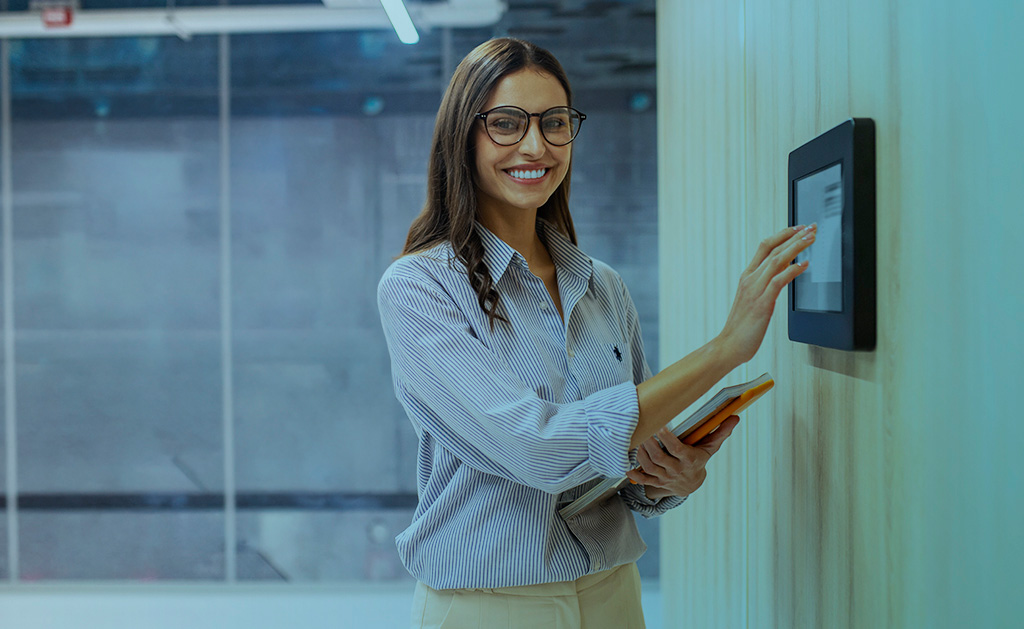 Mulher tocando painel de controle, sorrindo para a câmera. Com controle de ponto para equipe externa em obras.